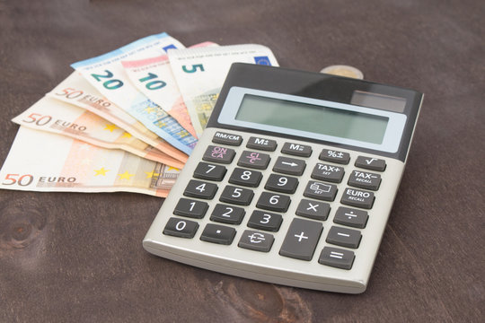 Banknotes and coins with calculator. Euro banknotes on wooden background. Photo for tax, profit and costing. 50 euro, 20 euro, 10 euro. Money and finance