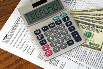 calculator with refund text sign on 1040 income tax form and American hundred dollar bills