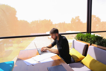 Freelance copywriter rewrite text on laptop at cafe table.
