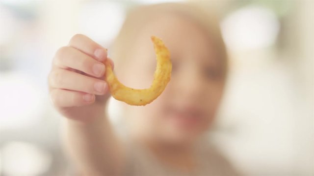 Focusing shot of a child holding a curly frie at an outdoor food court