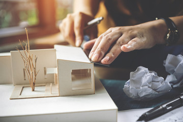 Closeup image of an architect measure scale of a mass model on table in office