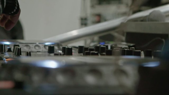 Male DJ play the music on the mixing console in the nightclub, closeup slow motion shot.