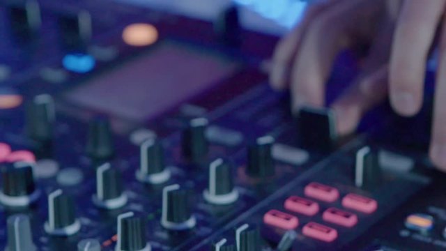 Male DJ play the music on the mixing console in the nightclub, closeup slow motion shot.
