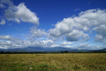 Picturesque white clouds and blue clouds over a vast field in Panama, bright sunny day