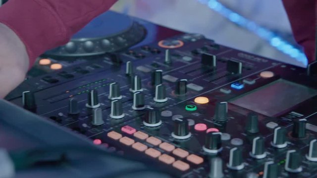 Male DJ play the music on the mixing console in the nightclub, closeup slow motion shot.