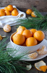 Mandarins in a bowl and twigs of cedar on a wooden table