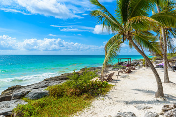 Obraz na płótnie Canvas Chairs under the palm trees on paradise beach at tropical Resort. Riviera Maya - Caribbean coast at Tulum in Quintana Roo, Mexico