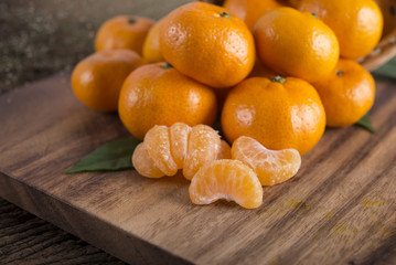 pile of whole and peeled fresh Tangerine or Mandarin orange on cutting board