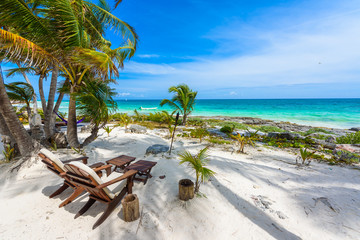 Chairs under the palm trees on paradise beach at tropical Resort. Riviera Maya - Caribbean coast at...