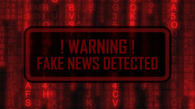 The text Warning, fake news detected, appearing on a board over random symbols falling down (code rain, a popular sci-fi movie effect), changing their color from green to red.
