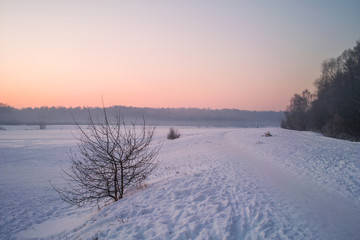 Winter sunset on the frozen lake in park