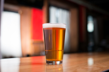 Pint of pale ale on a wood counter at a bar