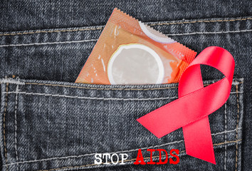Condom pack and red awareness ribbon on jeans pocket. AIDS and HIV awareness concept.