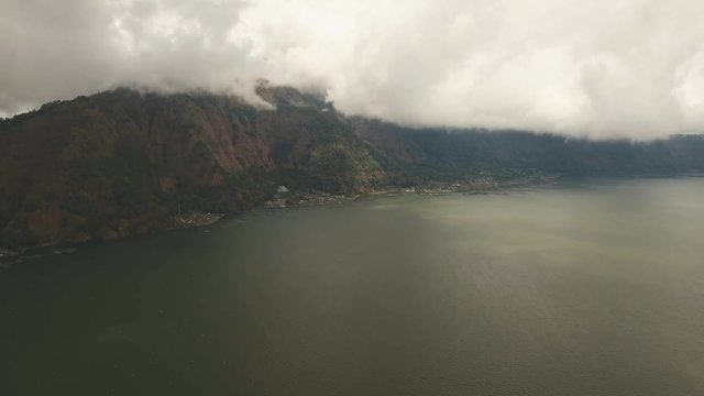Lake Batur in the crater of a volcano. Aerial view of volcano mount and lake Batur located in Kintamani area in Bali, Indonesia. Landscape, lake, mountains, clouds. 4K video. Travel concept. Aerial