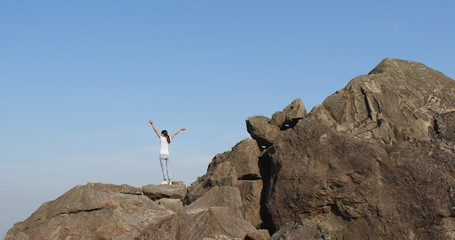 Fototapeta premium Woman hiker standing on rock on top of hill