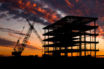 Steel construction site at sunset with a crane.