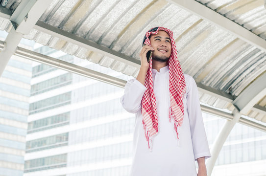 muslim businessman in traditional clothes talking on cell phone