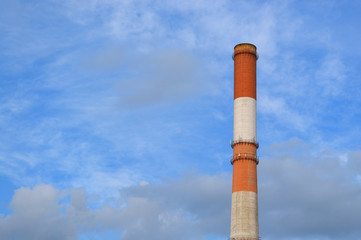 Old energy plant steam chimney in bright sky with picturesque clouds, industrial landscape