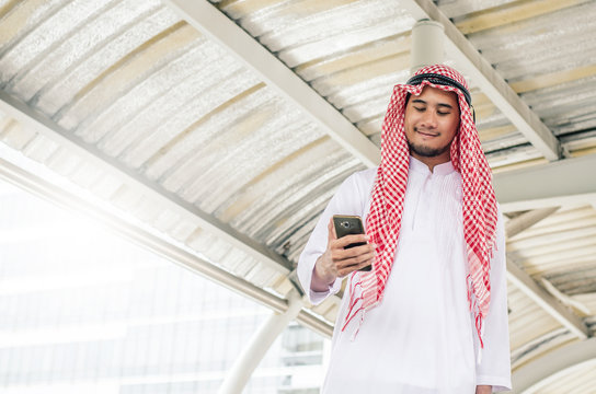 Young Arab businessman using mobile phone while walking in the city.