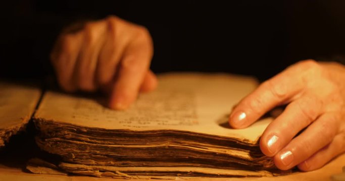 Elderly woman reading old book by candlelight

