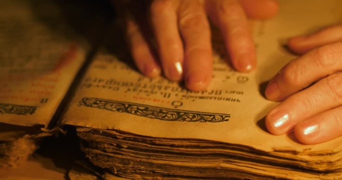 Elderly woman reading old book by candlelight

