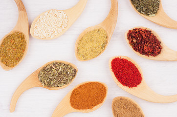 Asian spices in wooden spoons on soft white board, pattern, closeup.