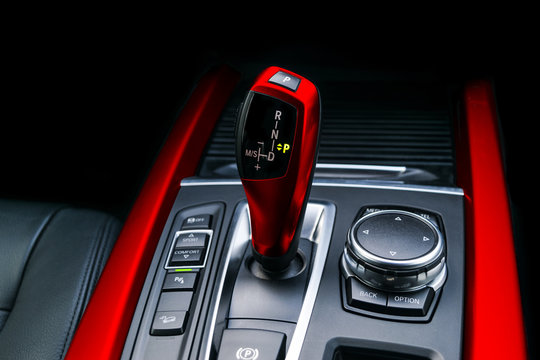 Red Automatic gear stick (transmission) of a modern car, multimedia and navigation control buttons. Car interior details. Transmission shift.