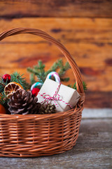 Fototapeta na wymiar Basket with Christmas gifts, decorations and fir branches on wooden background