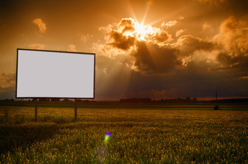 standing alone billboard in a field on a background of clouds and a passing sun