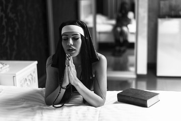 Young sexy woman nun praying and stay on knees