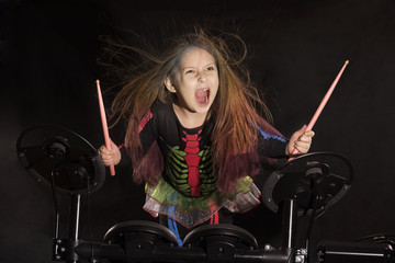 Little caucasian girl drummer with multicolored hair playing the electronic drum kit