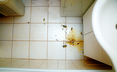 Colorful stains and broken glass on white bathroom tiles.