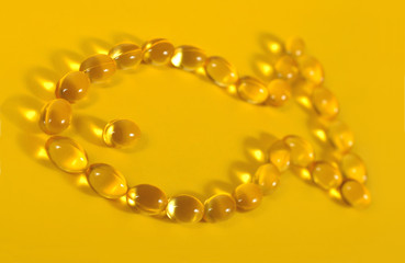 Omega-3 fish fat oil capsules shaped in fish on a yellow