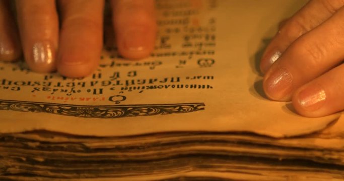 Elderly woman reading old book by candlelight