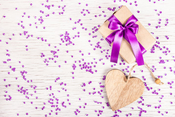Bright gift box with satin bow and wooden heart on a white background with rhinestones. Copy space. St. Valentine's Day