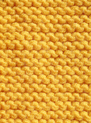 Knitting from woolen threads of orange color. Texture of handkerchief cloth.