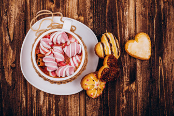 Cup with hot chocolates and marshmallows stands on the table with cookies