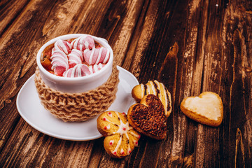 Cup with hot chocolates and marshmallows stands on the table with cookies