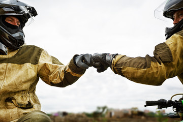 Two motorcyclists greet each other passing by