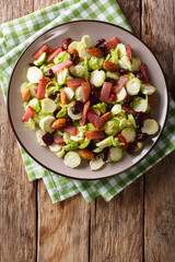 Delicious salad from Brussels sprouts, dried cranberries, almonds and ham close-up. Vertical top view