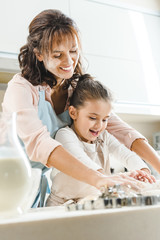 mother with daughter kneading dough