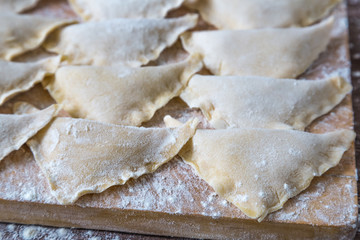    Dumplings kreplach on a cutting Board dusted with flour closeup. National Jewish dish.