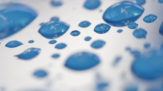 DOF, MACRO, CLOSE UP: Different sized raindrops sparkling on the surface of light blue car's roof. Detailed condensation on blue surface. Shiny transparent bubbles on wet car roof after light shower.