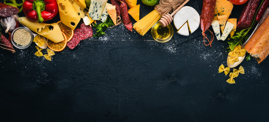 Assorted cheeses, sausages, wines, traditional spices and fresh vegetables on a wooden background. Cheese brie, blue cheese, gorgonzola, fuete, salami. Italian and Spanish Cuisine. Free space.