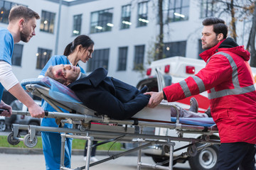 doctors moving injured man on ambulance stretcher