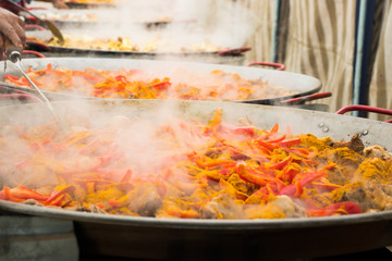 Vegetables, spices and chicken meat are steamed in giant pans to prepare a collective paella.