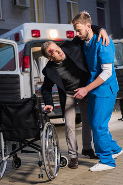 paramedic helping injured patient to sit in wheelchair