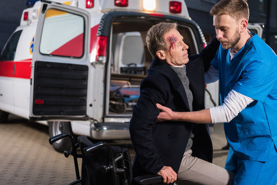 paramedic helping injured man to sit on wheelchair
