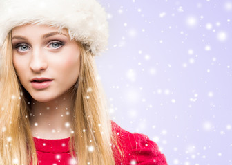 Portrait of young and beautiful girl in Christmas hat over winter background