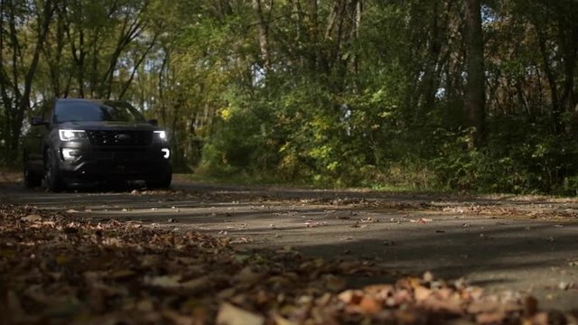Speeding SUV Car Ford Explorer Through the Forest During Fall Time. Slow Motion Footage